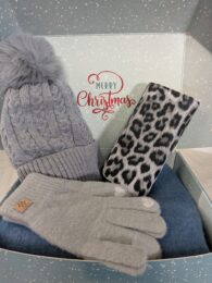 Grey winter gift box containing a grey bobble hat, grey gloves, blue fluffy scarf and a leopard purse arranged inside a festive Christmas box.
